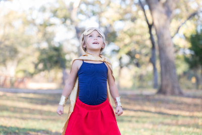 Adorable little girl pretending to be superhero outdoors